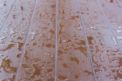 Water beads on a flooded wooden floor.